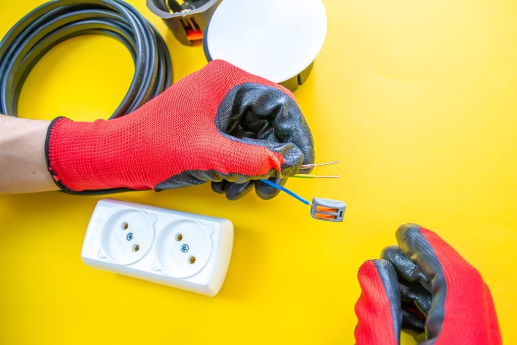 Boîtier mural ouvert avec neuf fils électriques de couleurs différentes prêts à être raccordés sur une prise