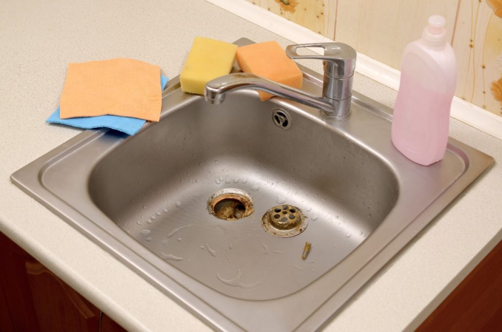Un évier de cuisine en inox et des produits de nettoyage