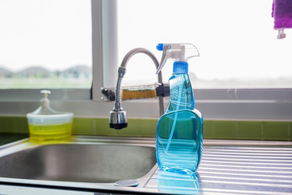 Un flacon nettoyant spray sur un évier de cuisine en inox