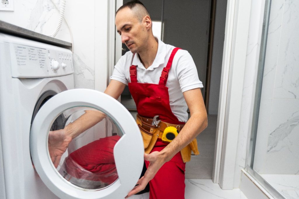Un homme faisant une réparation du lave-linge