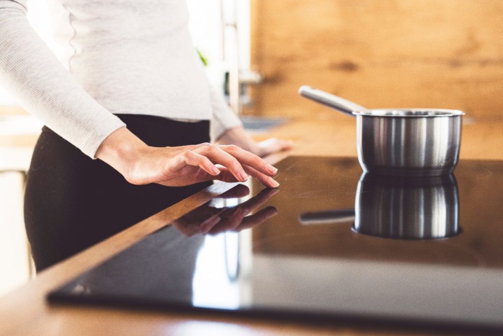 Une femme qui utilise une plaque induction dans la cuisine