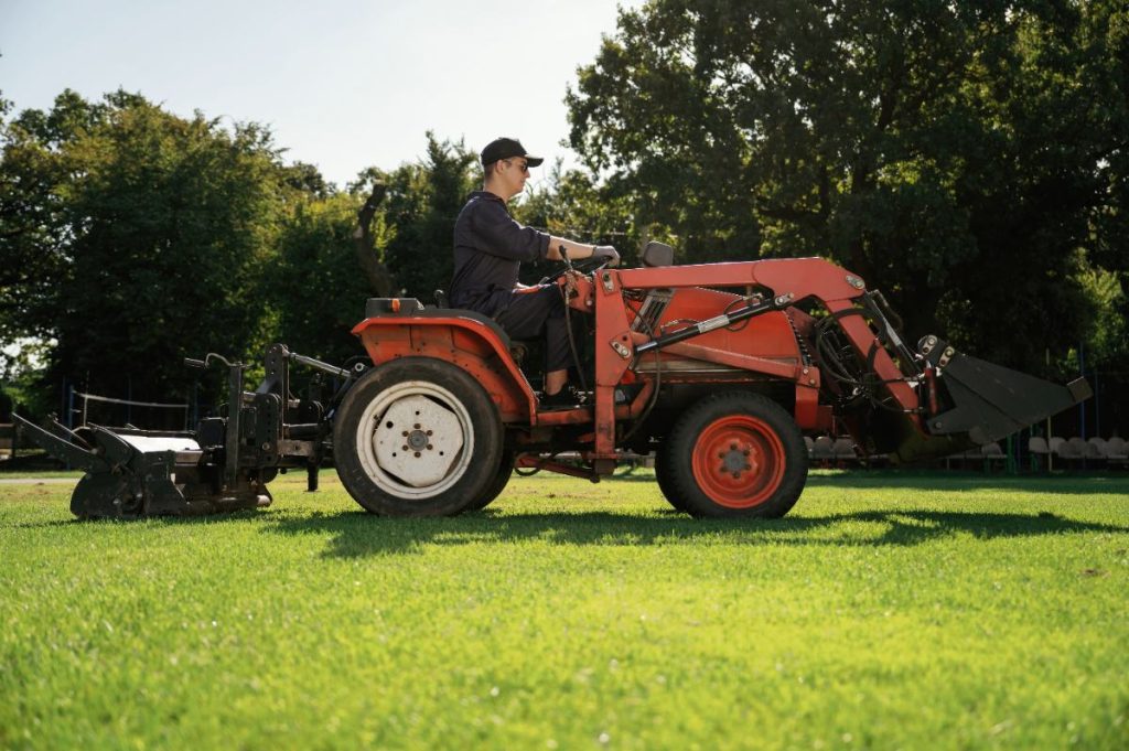 Un homme qui conduit un kubota sur une un champ vert