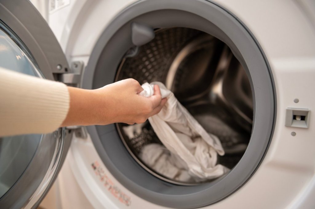 Main d'une femme sortant du vêtement dans la machine à laver