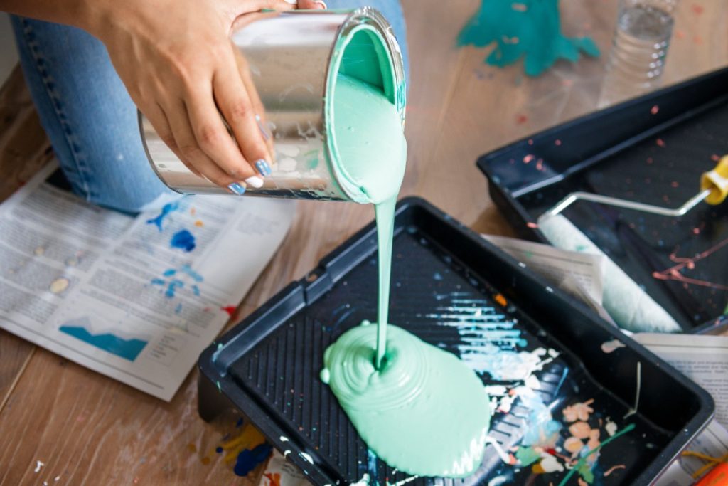 Une personne qui verse de la peinture bleu clair dans un plateau