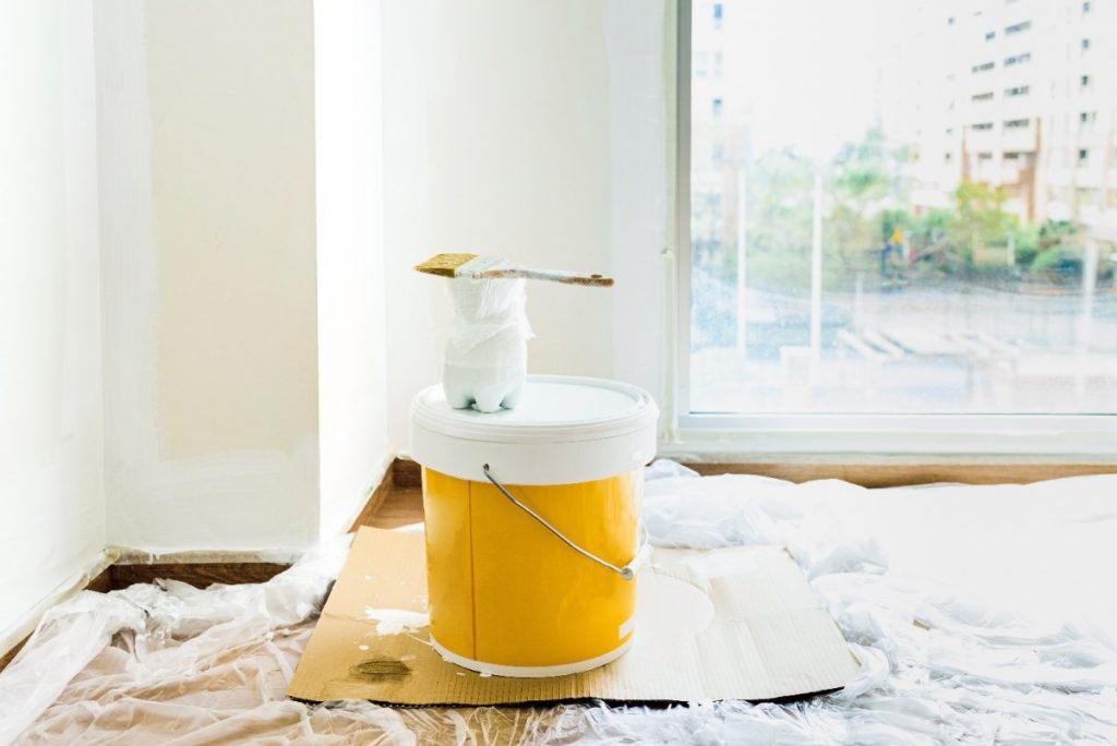 Un seau de peinture jaune et un pinceau