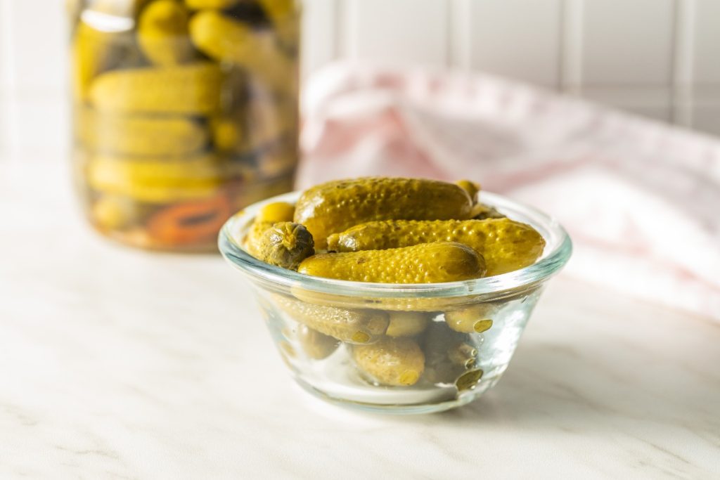 Comment préparer des cornichons maison sans passer par l'étape du dégorgement ? Un bol et un bocal rempli de cornichons