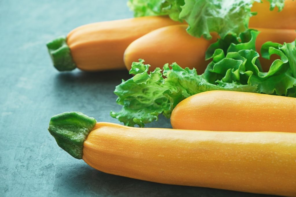 Des courgettes jaunes avec des laitues sur la table