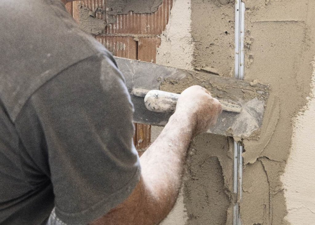 Un homme appliquant du mâchefer sur le mur