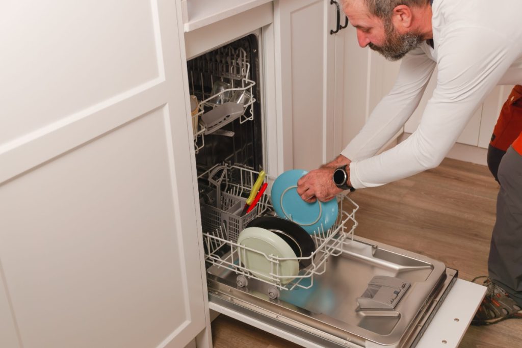 Un homme chargeant la lave-vaisselle avec des assiettes