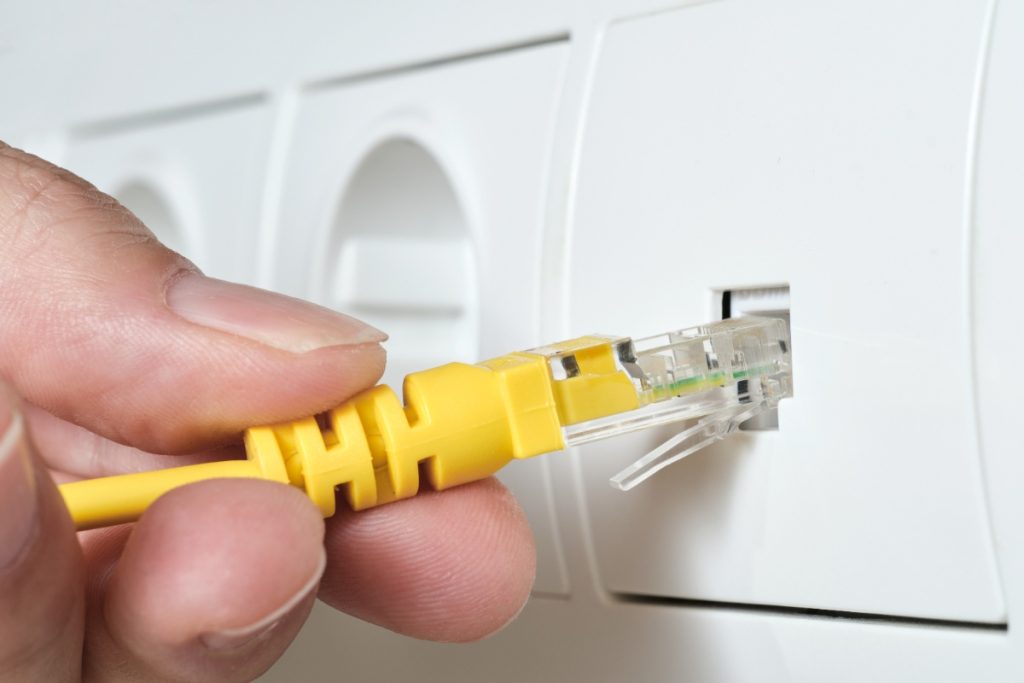 Main branchant du câble internet sur la prise murale