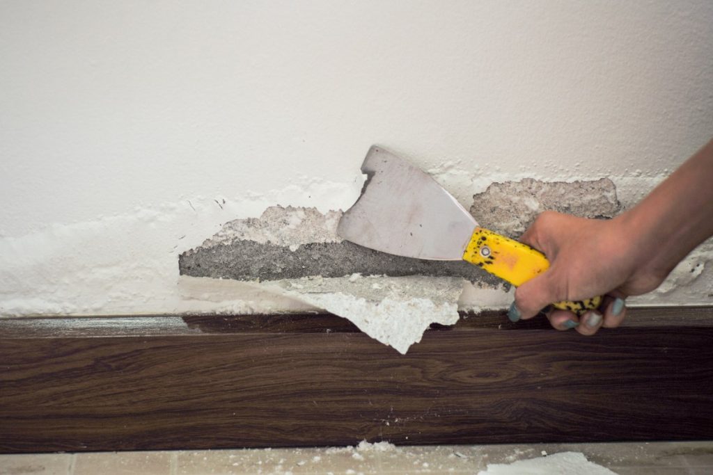 Comment appliquer un enduit sur du bois pour le protéger durablement ? Main utilisant un spatule pour enduire du bois