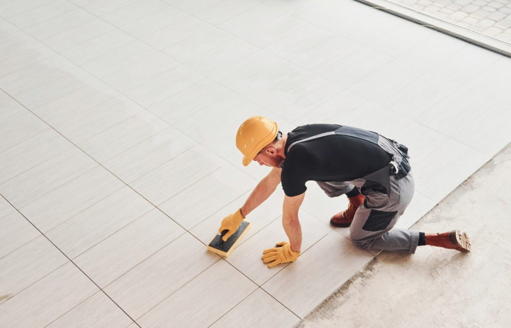 Quelle surface un carreleur professionnel peut-il couvrir en une journée de travail ? Un ouvrier posant du carrelage sur le sol