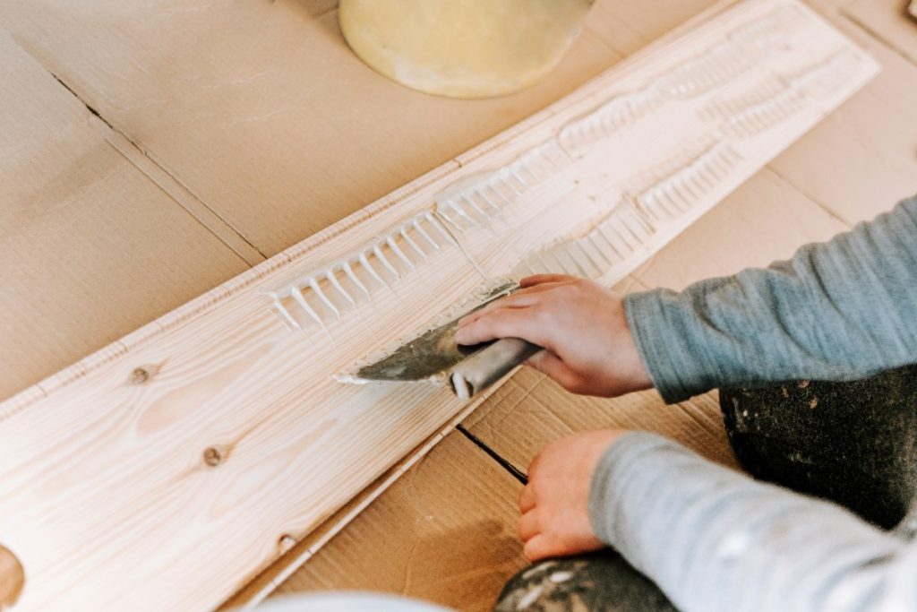 Comment appliquer un enduit sur du bois pour le protéger durablement ? Une personne qui applique de l'enduit sur du bois