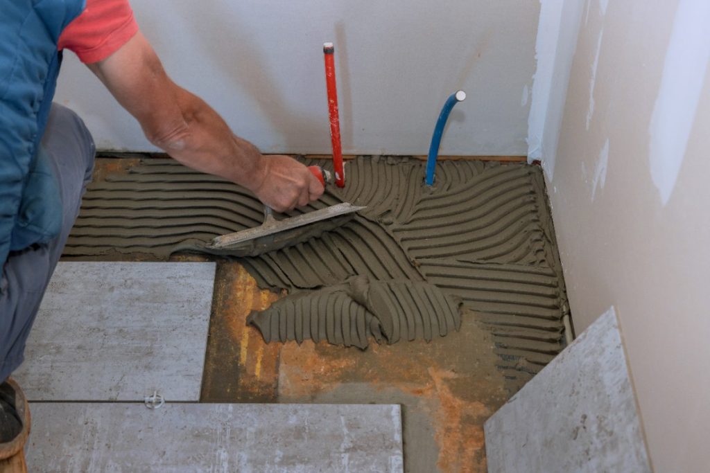 Un homme installant du carrelage dans une maison