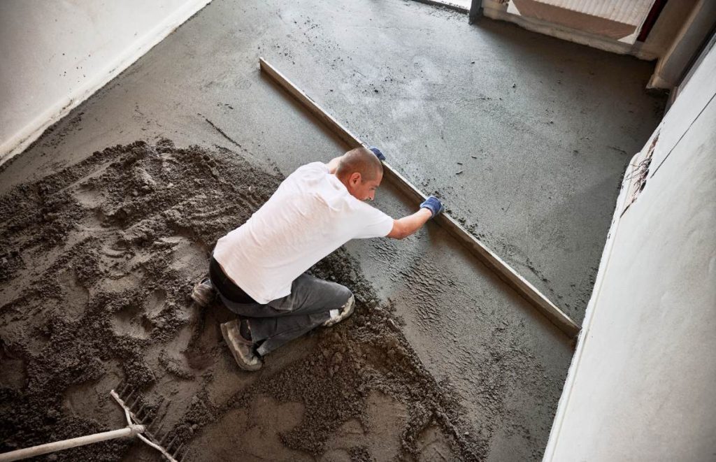 Un homme lissant le sol en béton