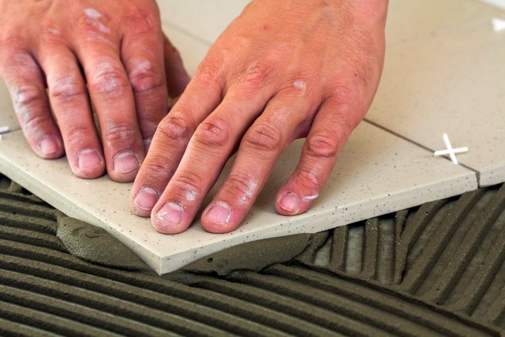 Mains posant du carrelage beige