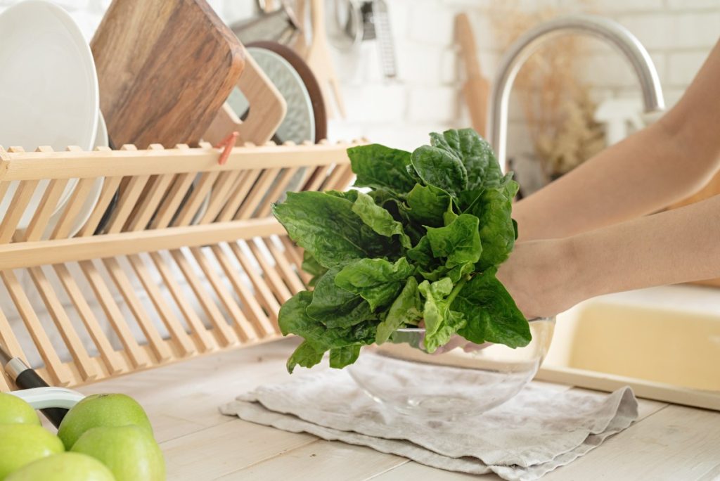 Mains tenant des feuilles vertes dans la cuisine