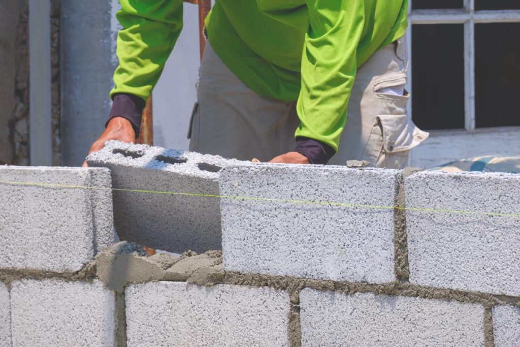Un ouvrier construisant un bâtiment avec des blocs de béton