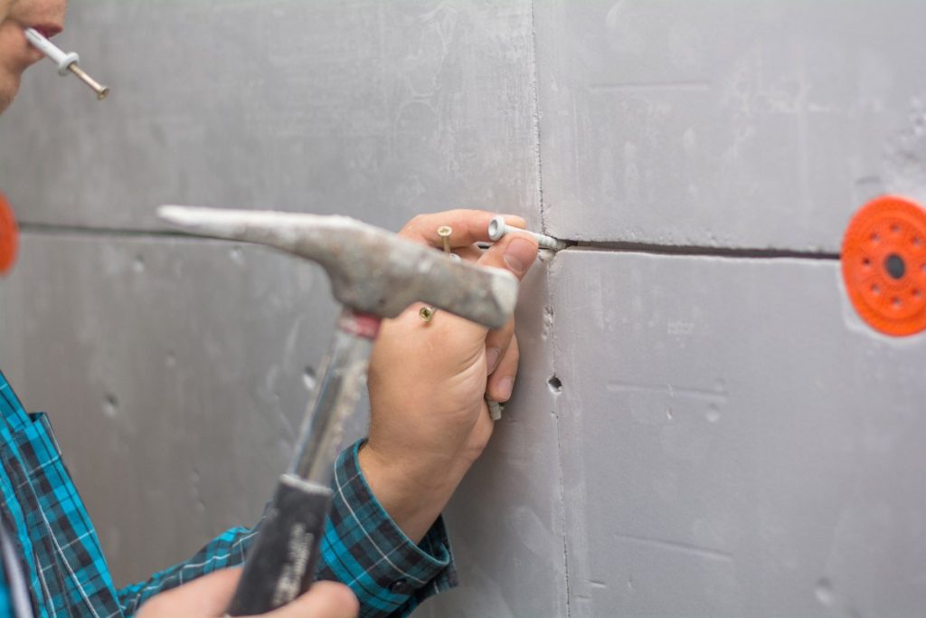Un ouvrier fixant le placo avec un marteau