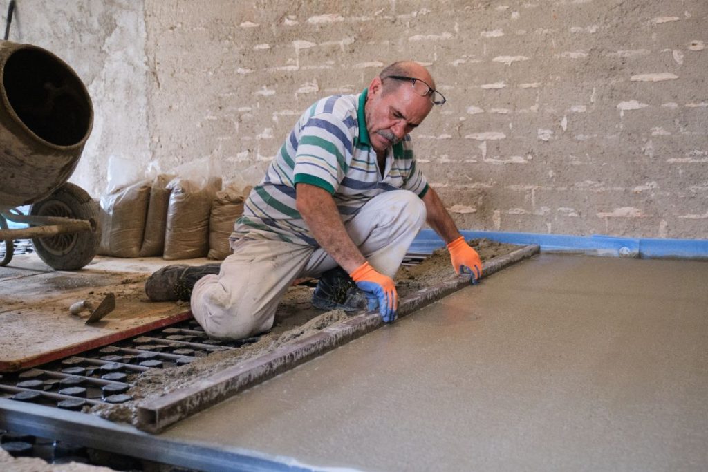 Un ouvrier lissant du ciment coulé sur un chantier