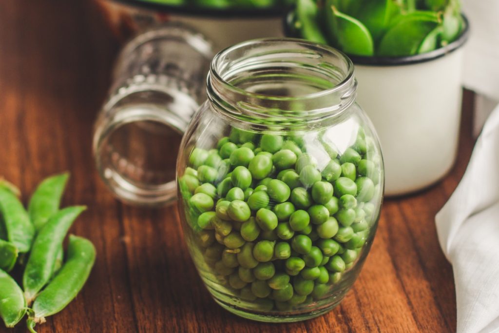 Des petits pois frais dans un bocal en verre sur la table