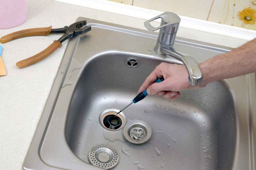 Un plombier réparant une bonde de lavabo