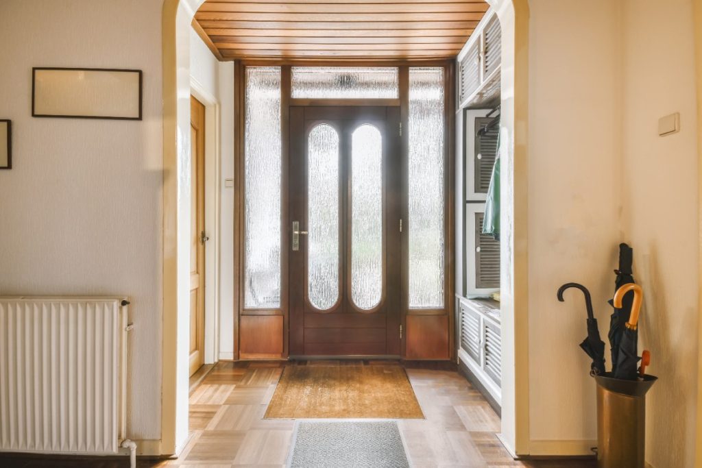 Un couloir avec une porte en bois et du sol carrelé