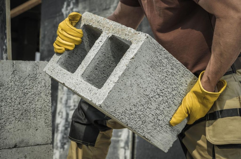Un ouvrier soulevant un parpaing sur un chantier